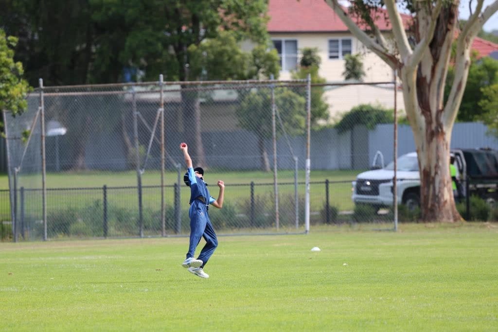 Ethan leaping in the outfield, holding the ball up high after taking a catch