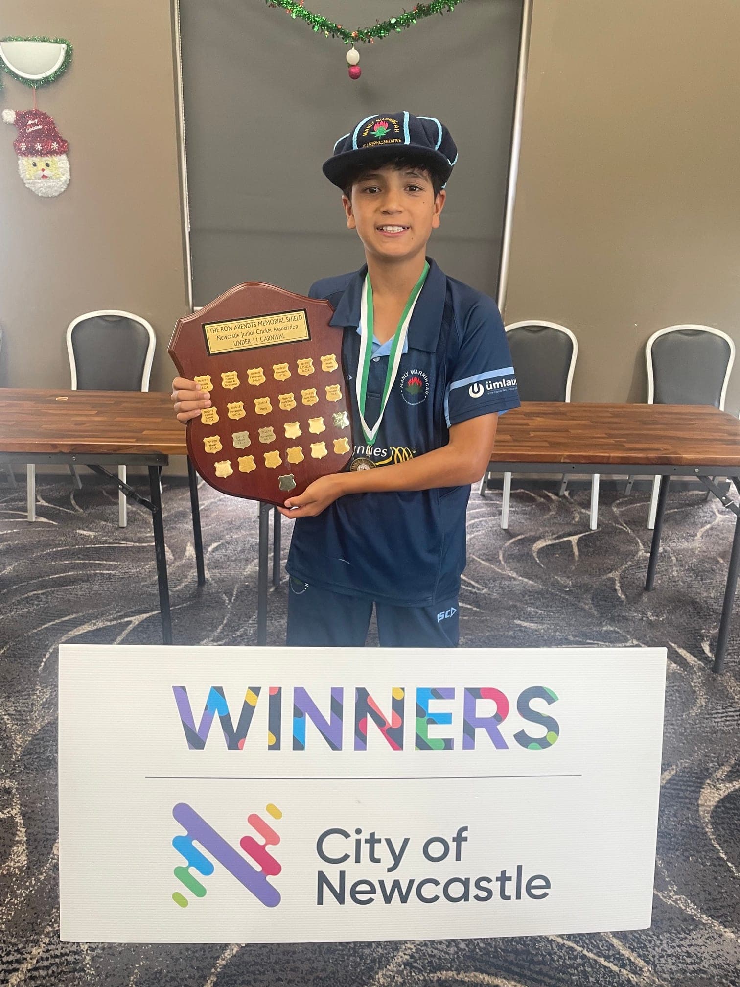 Ethan holding a championship shield after his representative cricket team won