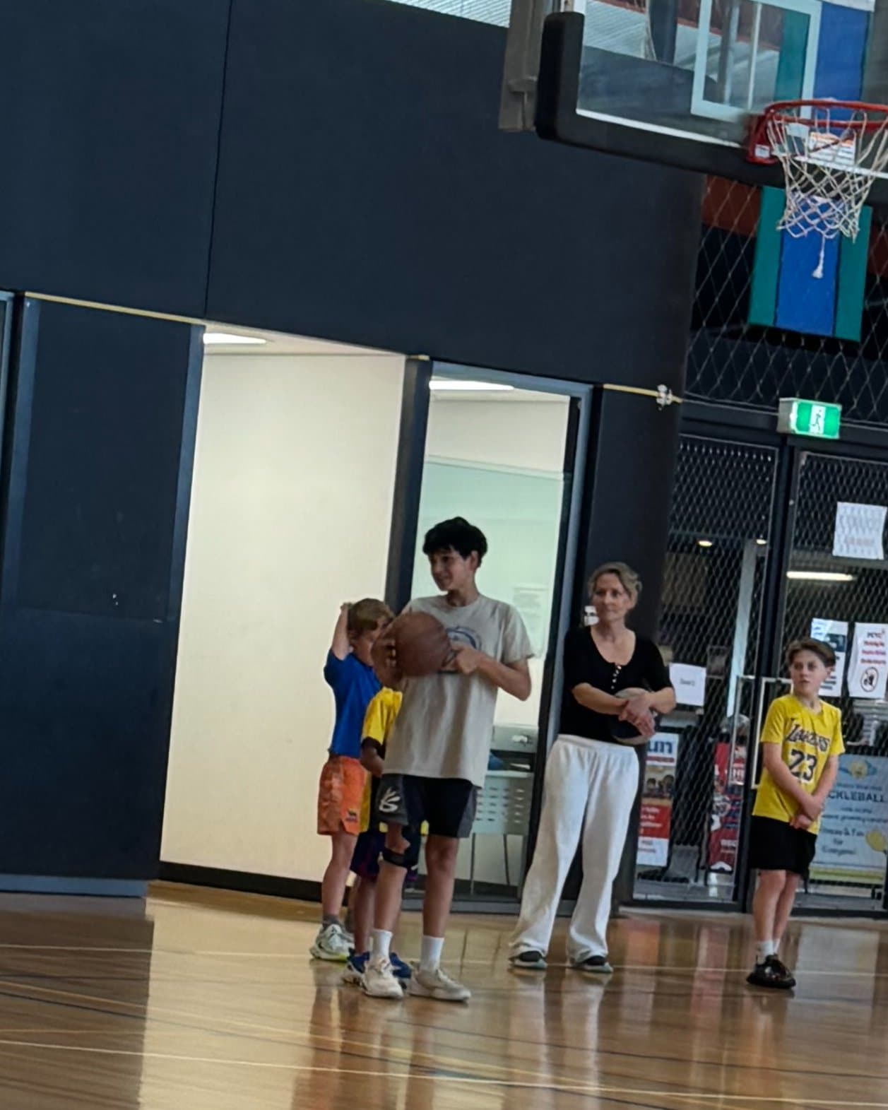Ethan holding a basketball with younger players at an indoor court